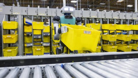 Un robot de Amazon en un centro logístico colocando un tote en una cinta.
